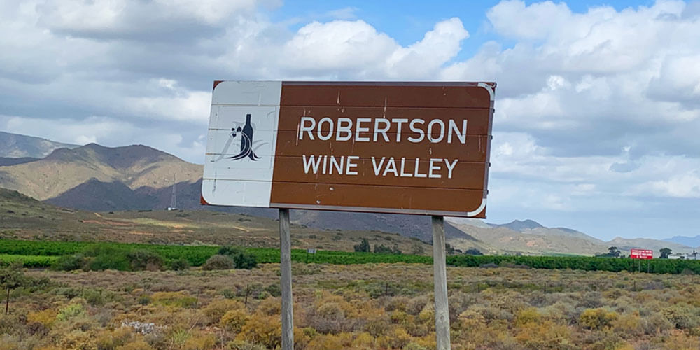Landschaft mit Hinweisschild zur Weinanbauregion Robertson in Südafrika