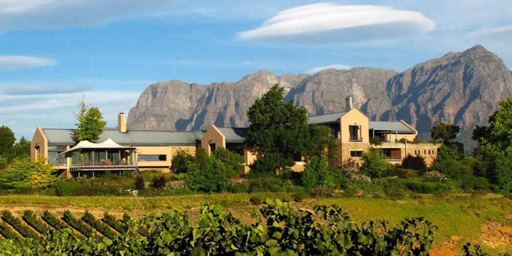Landschaftsaufnahme mit Blick auf das Weingut Tokara vor einem Bergmassiv in der Region Stellenbosch in Südafrika
