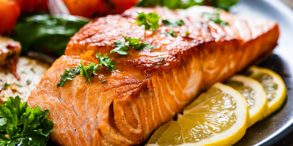 Frischer Lachs schön angerichtet auf einem Teller mit Gemüse Zitronenscheiben und Kräutern