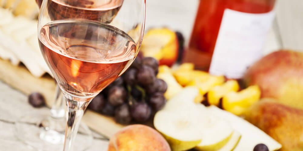 Stimmungsvolles Bild mit einem Glas Roséwein vor sommerlichem Obst